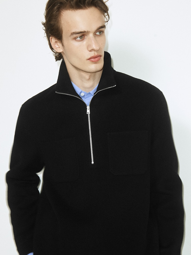 man wearing turtleneck standing on balcony